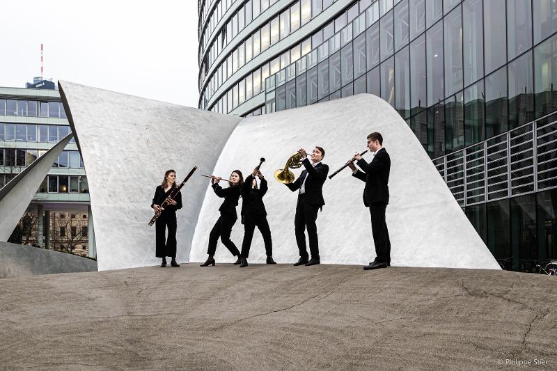 Die Gruppe steht vor einer Skulptur mit ihrem Musikinstrumenten in der Hand